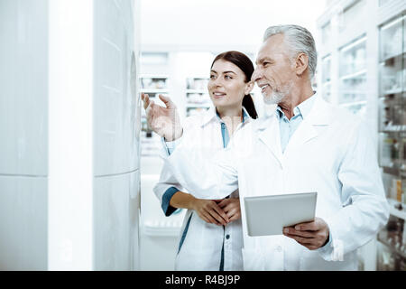 Your obligations. Kind bearded man expressing positivity and pointing at goods in shopwindow Stock Photo
