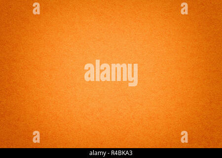 Texture of vintage dark ginger paper background with vignette. Structure of dense orange kraft cardboard with frame. Felt red gradient backdrop closeu Stock Photo