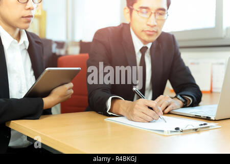 Business executive signing contracts with secretary at desk in office. Stock Photo