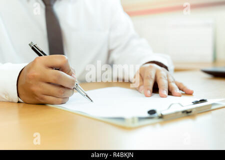 Businessman signing contract paper with pen in office desk. Stock Photo