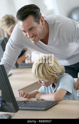 Schoolboy in computer lab with teacher helping Stock Photo - Alamy