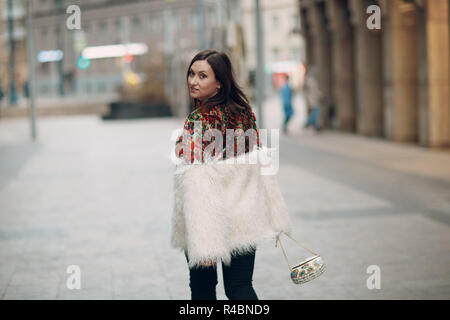 Young stylish woman in fur coat walking street Stock Photo