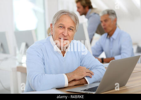 Portrait of senior man working on laptop, training class Stock Photo