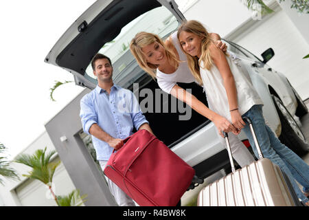 Parents with child putting luggage in car trunk Stock Photo