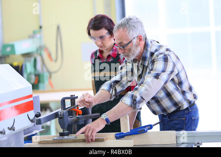 Carpenter showing apprentice how to use sawing machine Stock Photo - Alamy