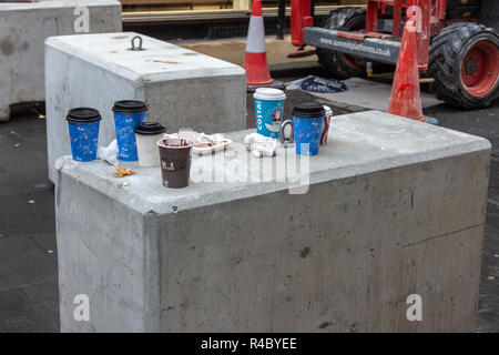 Discarded festive costa disposable cups and food wrappings left as litter on a concrete block in front of cones and machinery from building work Stock Photo