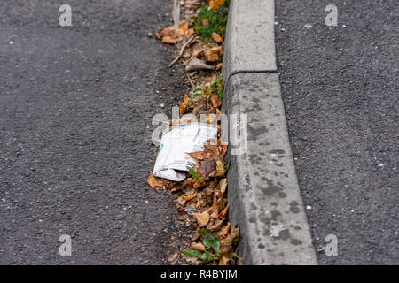 A flattened crushed discarded Starbucks cardboard takeaway cup that has been dropped as litter by the pavement kerbstones at the side of the road Stock Photo