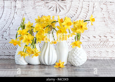 Close-up, still-life image of the beautiful spring flowers of Narcissus 'Tete-a-Tete' a dwarf Daffodil. cut flowers in white porcelain vases Stock Photo