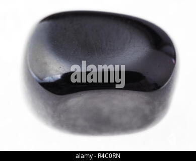 macro photography of natural mineral from geological collection - tumbled black Onyx stone on white background Stock Photo