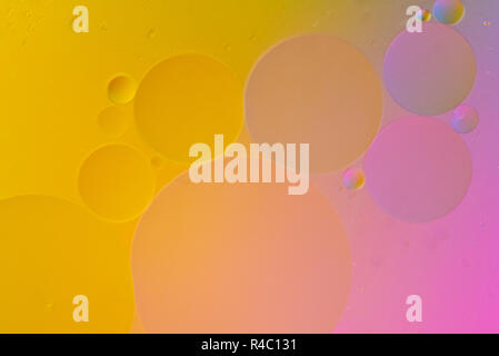 Artistic macro picture of oil droplets floating on water with a coloured background Stock Photo