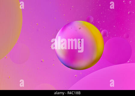 Artistic macro picture of oil droplets floating on water with a coloured background Stock Photo