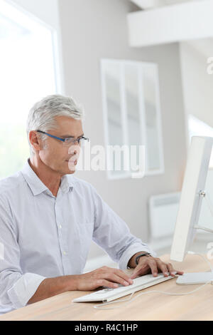 Senior man connected on desktop computer Stock Photo