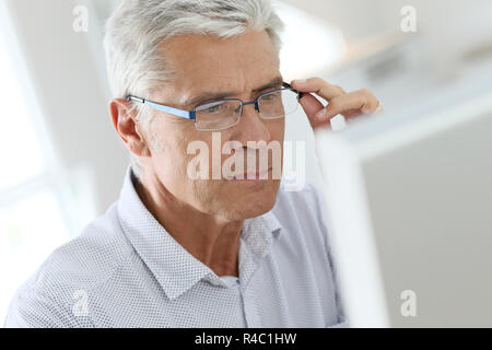 Senior man connected on desktop computer Stock Photo