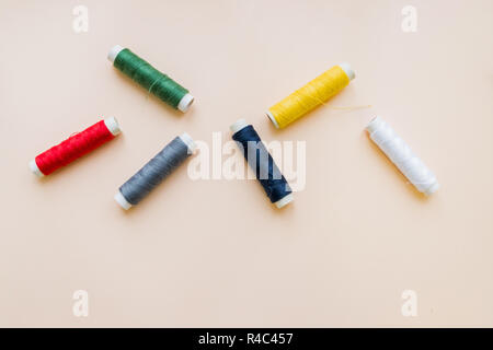 collection of various sewing threads on pastel background. each one is shot separately. knittinng tools.Natural cotton string roll isolated, copy space.Colored thread coils multi colored embroidery thread yarns. Stock Photo