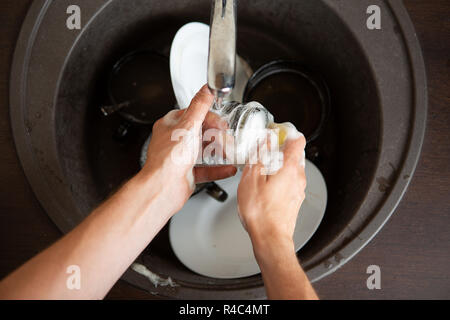 Picture from above of man's hands washing dish into sink Stock Photo