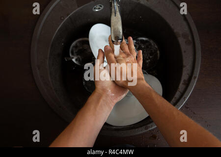 Photo from above of man's hands washing white plates Stock Photo