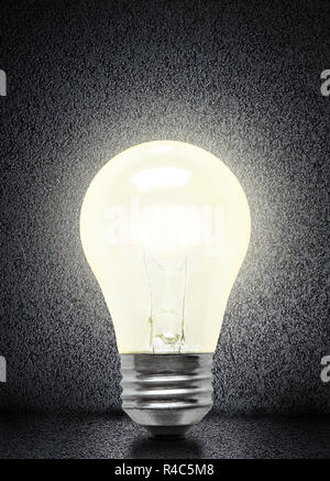 Glowing electrical incandescent light bulb isolated on asphalt background with copy space. Stock Photo