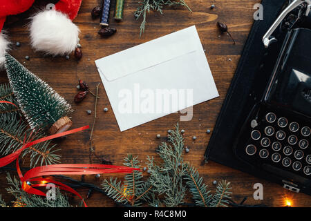 Writing a letter to Santa Claus for Christmas, blank envelope on table among festive holiday decoration Stock Photo