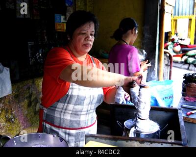 ANTIPOLO CITY, PHILIPPINES - NOVEMBER 24, 2018: A food vendor cooks Puto Bumbong or ground glutenous rice steamed in bamboo at her store. Stock Photo