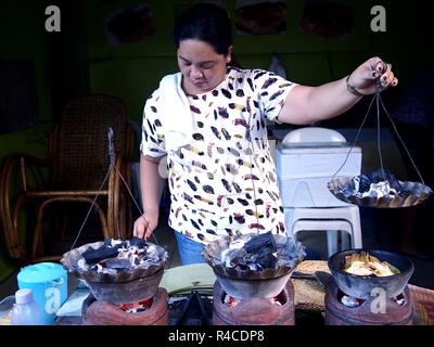 ANTIPOLO CITY, PHILIPPINES - NOVEMBER 24, 2018: A food vendor cooks Bibingka or rice cake with salted egg at her store. Stock Photo