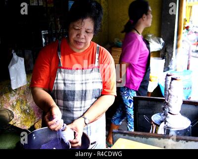 ANTIPOLO CITY, PHILIPPINES - NOVEMBER 24, 2018: A food vendor cooks Puto Bumbong or ground glutenous rice steamed in bamboo at her store. Stock Photo