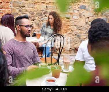 Young man talking with friends in a trendy cafe courtyard Stock Photo