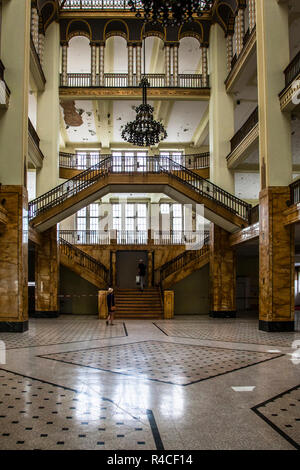 The vacant Görlitzer Warenhaus opens up a view of its double staircase beneath the glass-domed roof. The Art Nouveau department store opened on 30 September 1913 to designs by Potsdam architect Carl Schmanns under the name "Zum Strauß" on Demianiplatz, modelled on Berlin's Wertheim department store. It closed for good on 15 August 2009; in 2013 Görlitz entrepreneur Winfried Stöcker bought the building for restoration. It stands as Germany's only Art Nouveau department store preserved in its original condition. In 2013 the hall also served director Wes Anderson as a set for "The Grand Budapest  Stock Photo