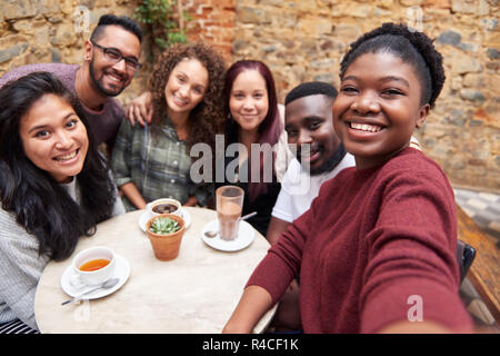 Diverse young friends taking selfies together in a cafe courtyard Stock Photo