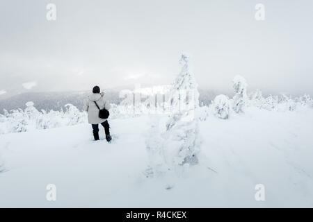 Alone photographer on mountain top in snowstorm with a backpack in winter time. Travel concept. Carpathian mountains. Landscape photography Stock Photo