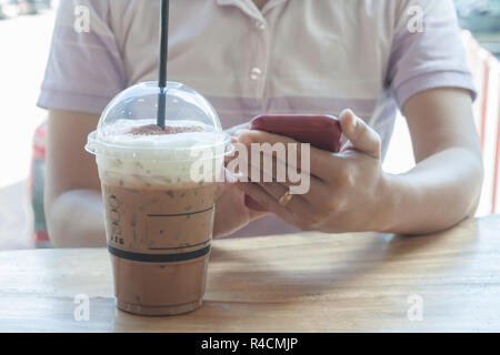 Woman hand holding phone with background of iced coffee Stock Photo