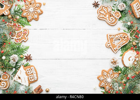 Christmas frame with rustic ornaments, spruce branches and Gingerbread cookies on white wood xmas background. Copy space. Stock Photo