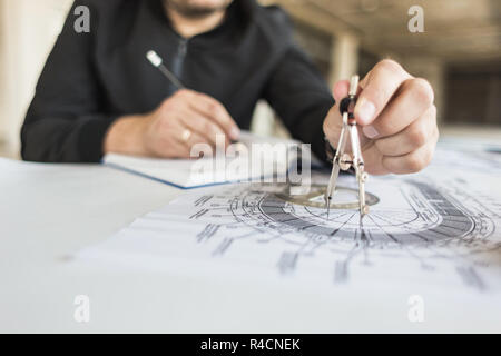 architect builder works at the table with drawings. Helmet, drawings, compasses in the workplace Stock Photo