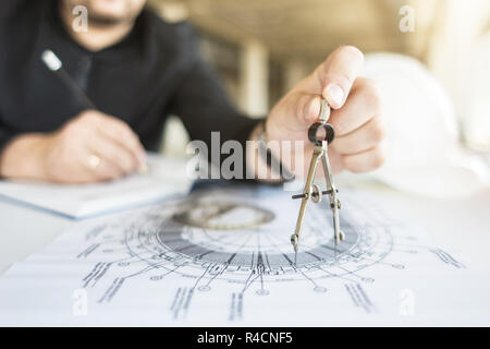 architect builder works at the table with drawings. Helmet, drawings, compasses in the workplace Stock Photo