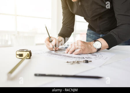architect builder works at the table with drawings. Helmet, drawings, compasses in the workplace Stock Photo