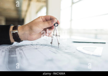 architect builder works at the table with drawings. Helmet, drawings, compasses in the workplace Stock Photo