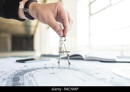 architect builder works at the table with drawings. Helmet, drawings, compasses in the workplace Stock Photo