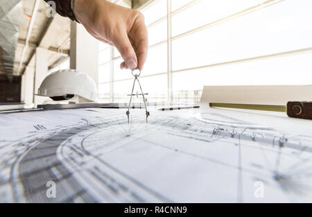 architect builder works at the table with drawings. Helmet, drawings, compasses in the workplace Stock Photo