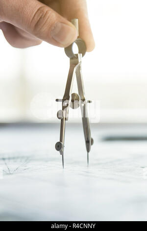 architect builder works at the table with drawings. Helmet, drawings, compasses in the workplace Stock Photo