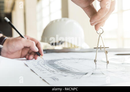 architect builder works at the table with drawings. Helmet, drawings, compasses in the workplace Stock Photo