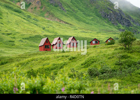 Abandoned red cabins sit in the green lush mountains of Alaska’s Hatcher Pass near Independence Mine. Stock Photo