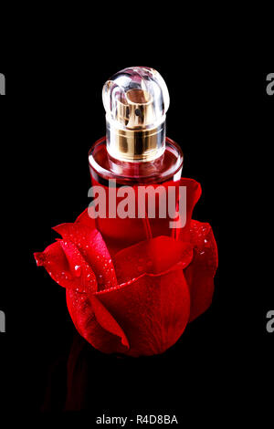 Glass of perfume in rose petals over black background presentation Stock Photo