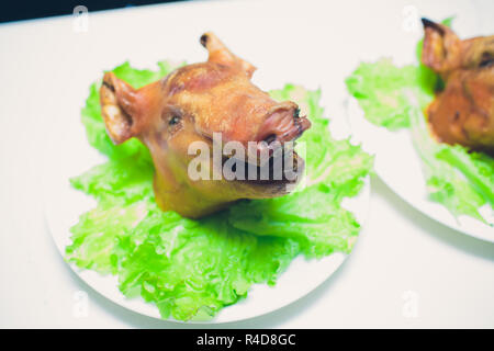 Grilled suckling pig on a plate in banquet restaurant. Stock Photo