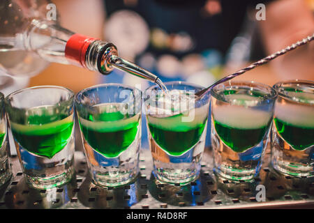 Green liquid in shot glasses standing on the counter. bartender preparing shots Stock Photo