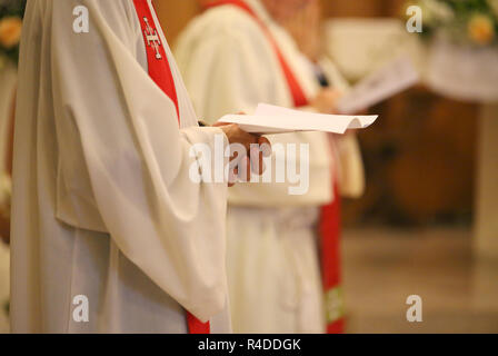 young priest with a cassock and hands joined in prayer during Holy Mass Stock Photo