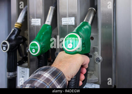 Man selecting petrol fuel pump nozzle at gas station for refueling his car in Europe Stock Photo