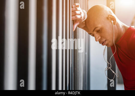 Sad tired man standing in his headphones Stock Photo