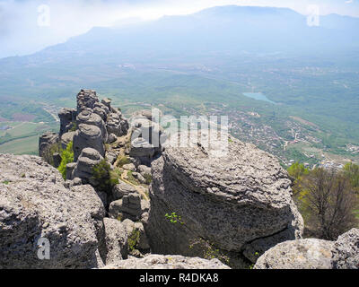 Beautiful mountain landscape with rounded rocks. Top view of the inhabited valley. Distant mountain plateaus in a blue haze and sea far below on the h