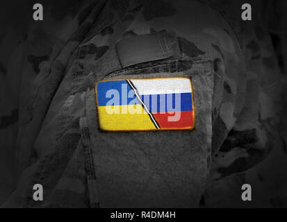 Ukraine vs Russia. Ukrainian Russian conflict. Flag of Ukraine and Russia at military uniform (collage) Stock Photo