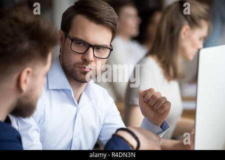 Serious focused male employee listening to colleague Stock Photo