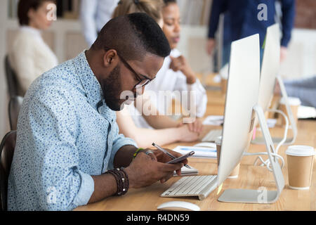 Serious African American man using smartphone at workplace Stock Photo